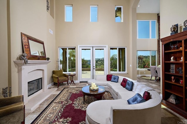 living room featuring a towering ceiling, a premium fireplace, french doors, and baseboards