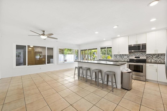 2348 Watson Way, Vista, CA 92081 - kitchen featuring stainless steel appliances, decorative backsplash, dark countertops, a breakfast bar, and plenty of natural light