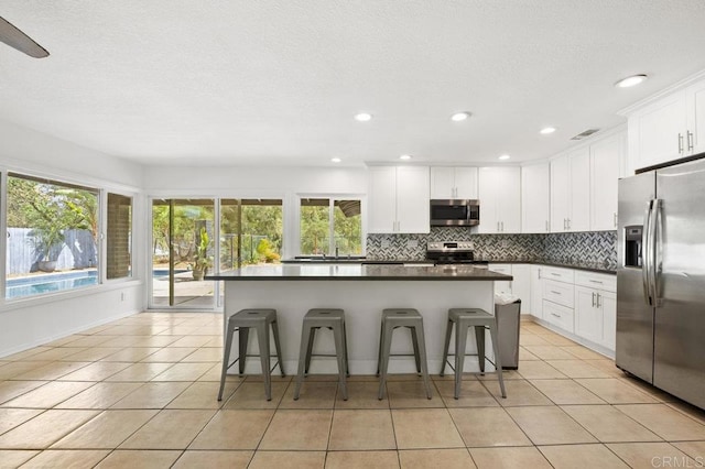 2348 Watson Way, Vista, CA 92081 - kitchen featuring appliances with stainless steel finishes, light tile patterned flooring, backsplash, dark countertops, and a breakfast bar