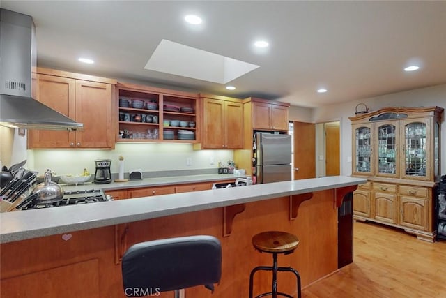 10647 Forbestown Rd, Challenge, CA 95925 - kitchen with wall chimney range hood, freestanding refrigerator, stove, a breakfast bar, and recessed lighting
