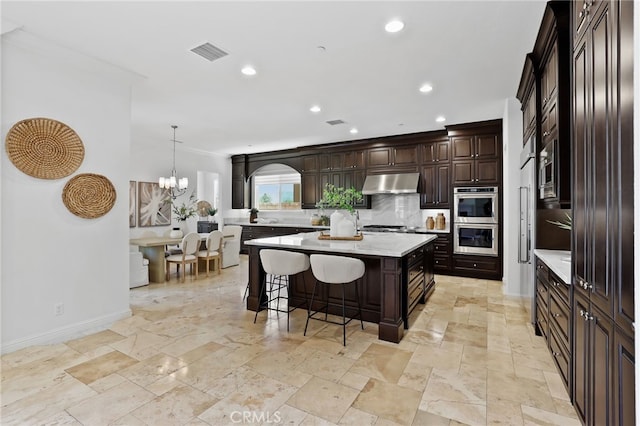 28 Dogwood, Lake Forest, CA 92630 - kitchen with under cabinet range hood, appliances with stainless steel finishes, a breakfast bar, baseboards, and a center island