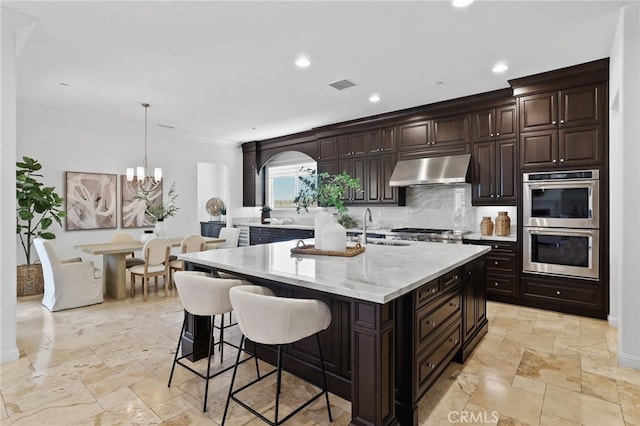 28 Dogwood, Lake Forest, CA 92630 - kitchen with under cabinet range hood, stainless steel appliances, stone tile floors, a sink, and recessed lighting