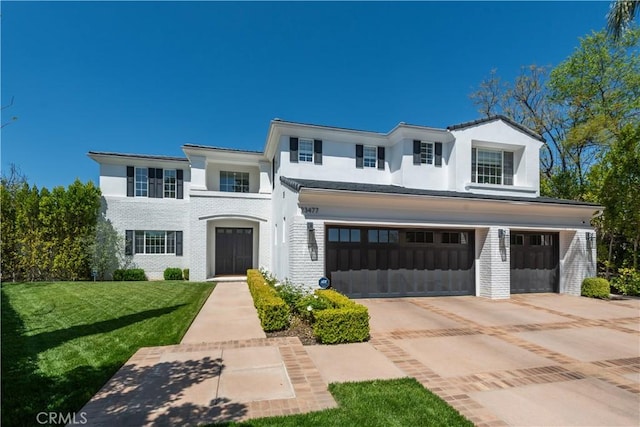 23477 Palm Dr, Calabasas, CA 91302 - view of front of home featuring an attached garage, a front yard, driveway, stucco siding, and brick siding