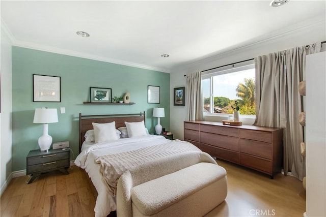 bedroom featuring light wood-style flooring, crown molding, and baseboards