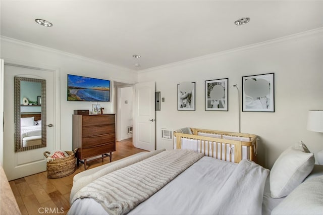 bedroom featuring ornamental molding and wood finished floors