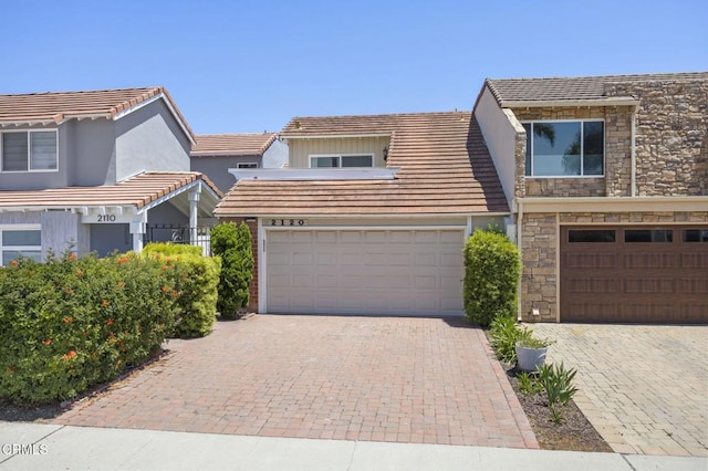 2120 Jamestown Way, Oxnard, CA 93035 - view of front of house with stone siding, a garage, driveway, stucco siding, and a tiled roof