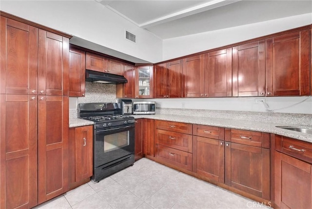 6109 N Traymore Ave, Azusa, CA 91702 - kitchen with black gas range oven, stainless steel microwave, under cabinet range hood, light stone counters, and tasteful backsplash