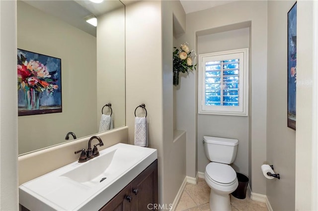 half bath featuring vanity, baseboards, toilet, and tile patterned floors
