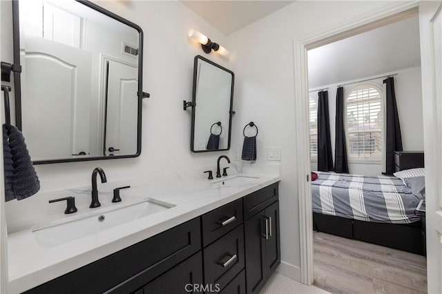 bathroom featuring connected bathroom, double vanity, and wood finished floors