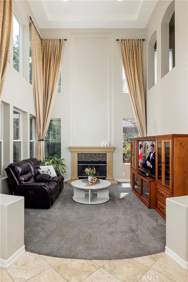 living area featuring carpet, a high ceiling, a fireplace, and arched walkways