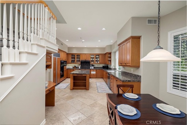 kitchen with open shelves, brown cabinets, stainless steel dishwasher, a center island, and a sink