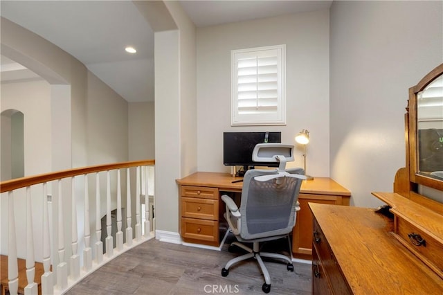 office area with dark wood-style flooring, arched walkways, and recessed lighting