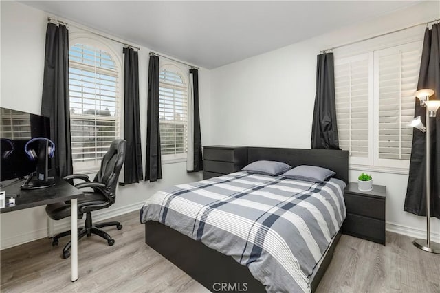 bedroom featuring wood finished floors, baseboards, and an office area
