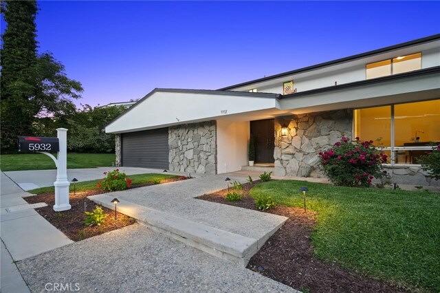 5932 Ellenview Ave, Woodland Hills, CA 91367 - view of front of house with stone siding, driveway, stucco siding, and a yard