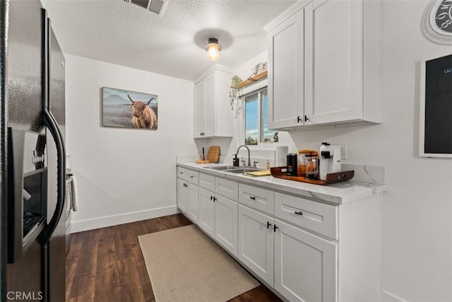 3872 Balsa Ave, Yucca Valley, CA 92284 - kitchen with black refrigerator with ice dispenser, dark wood-style flooring, baseboards, white cabinets, and a sink