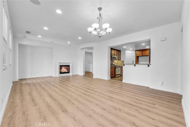 12455 Benton Dr Unit 2, Rancho Cucamonga, CA 91739 - unfurnished living room featuring recessed lighting, a chandelier, light wood-style floors, baseboards, and a glass covered fireplace