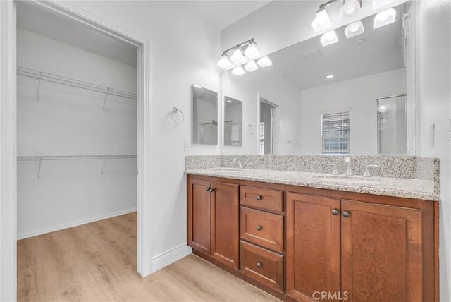 12455 Benton Dr Unit 2, Rancho Cucamonga, CA 91739 - bathroom featuring wood finished floors, double vanity, baseboards, and a walk in closet