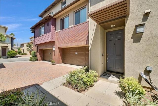12455 Benton Dr Unit 2, Rancho Cucamonga, CA 91739 - property entrance featuring an attached garage, stucco siding, driveway, and brick siding