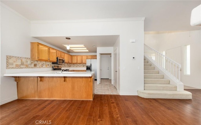 4919 Oakhurst Ave, Banning, CA 92220 - kitchen featuring stainless steel appliances, wood finished floors, a peninsula, light countertops, and tasteful backsplash