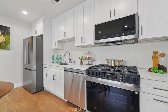 8142 Vantage Ave, North Hollywood, CA 91605 - kitchen with stainless steel appliances, a sink, light countertops, white cabinetry, and light wood-style flooring