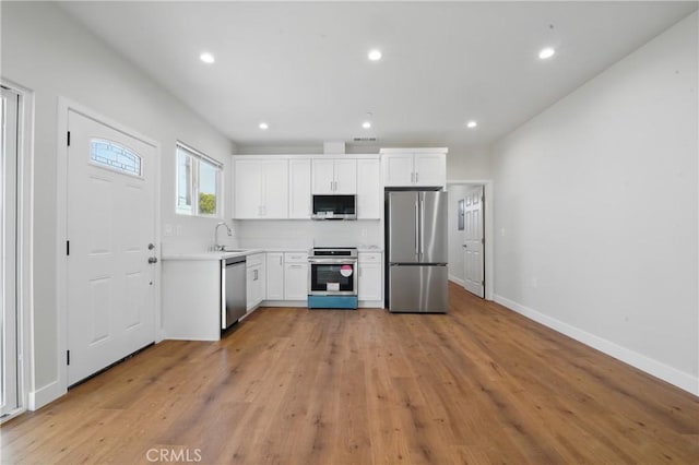 8142 Vantage Ave, North Hollywood, CA 91605 - kitchen with stainless steel appliances, a sink, white cabinets, light countertops, and light wood-style flooring