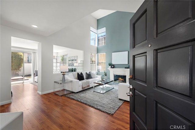 15283 Rousseau Ln, La Mirada, CA 90638 - living room with dark wood-type flooring, baseboards, a lit fireplace, recessed lighting, and a towering ceiling