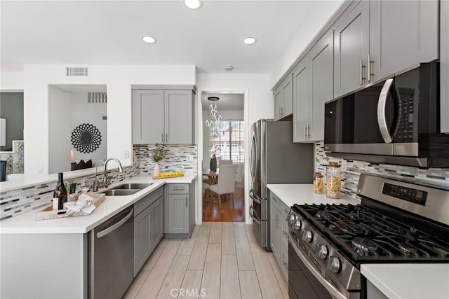 15283 Rousseau Ln, La Mirada, CA 90638 - kitchen featuring appliances with stainless steel finishes, gray cabinetry, light wood-type flooring, tasteful backsplash, and recessed lighting