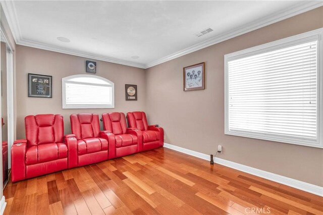 home theater room with light wood finished floors, baseboards, and ornamental molding