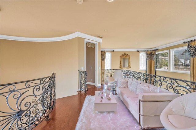 living area featuring wood finished floors, ornamental molding, and healthy amount of natural light
