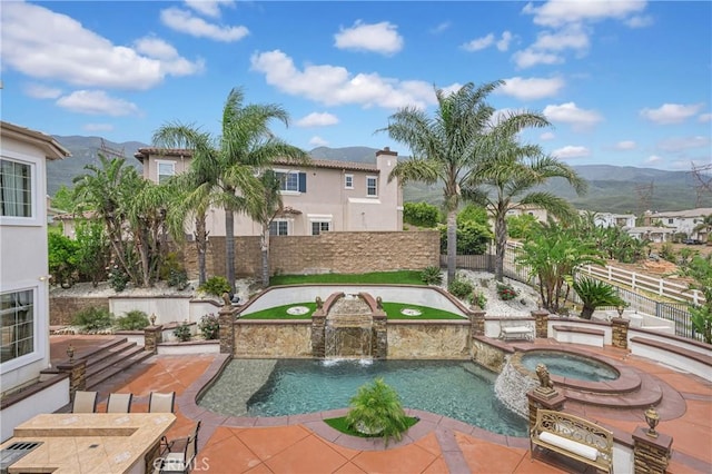 view of property's community featuring a jacuzzi, a patio area, a mountain view, a pool, and a fenced backyard