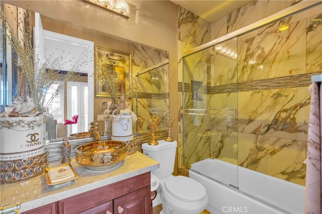 bathroom featuring toilet, bath / shower combo with glass door, and vanity