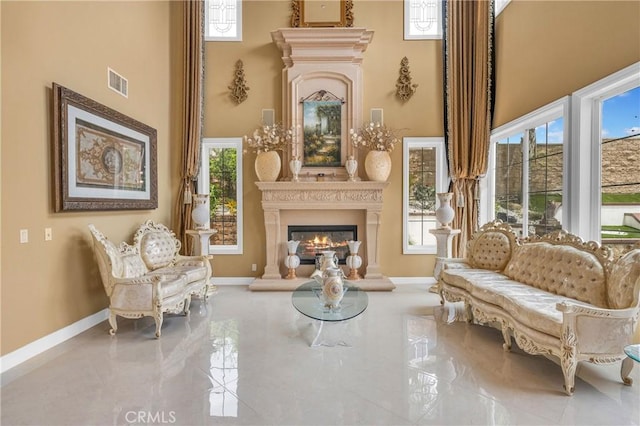sitting room with a high ceiling, a fireplace, and baseboards
