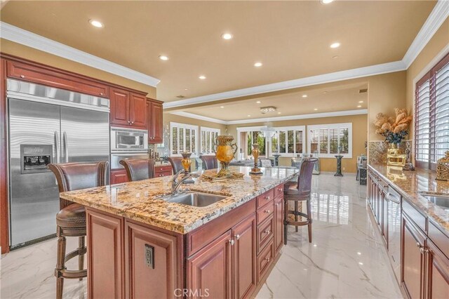 kitchen featuring built in appliances, a kitchen breakfast bar, a sink, light marble finish floors, and a warming drawer