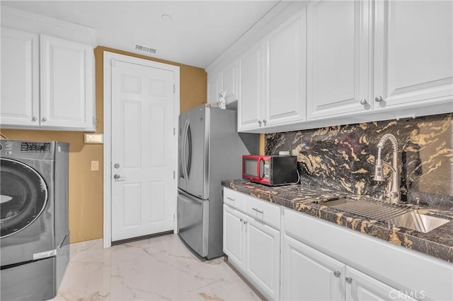 washroom featuring washer / dryer, light marble finish flooring, and cabinet space