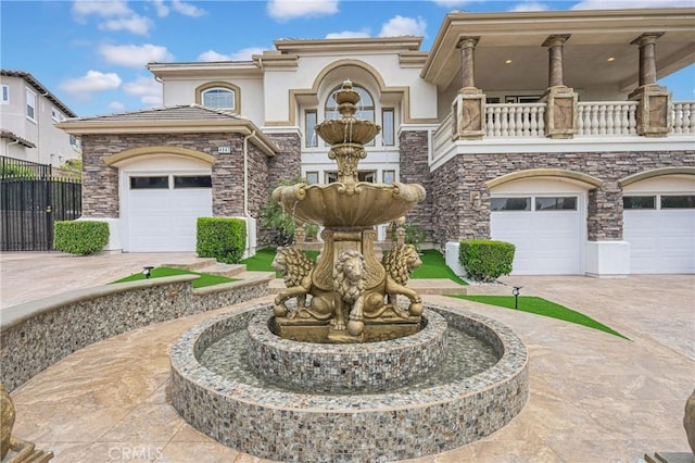 mediterranean / spanish home featuring fence, a balcony, concrete driveway, and stucco siding