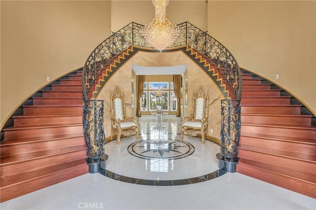staircase with a towering ceiling and a chandelier