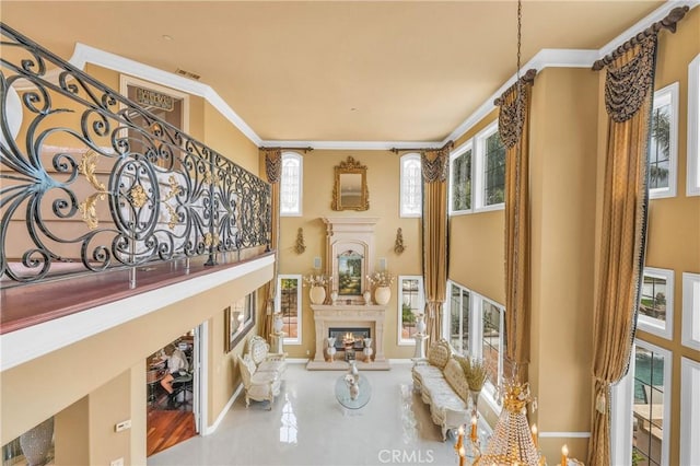living room with a warm lit fireplace, a high ceiling, baseboards, and crown molding