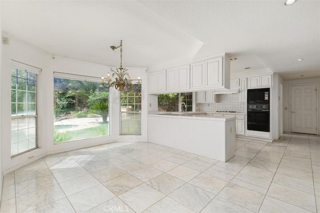 2484 Chauncy Pl, Riverside, CA 92506 - kitchen with black appliances, a peninsula, white cabinets, backsplash, and a chandelier