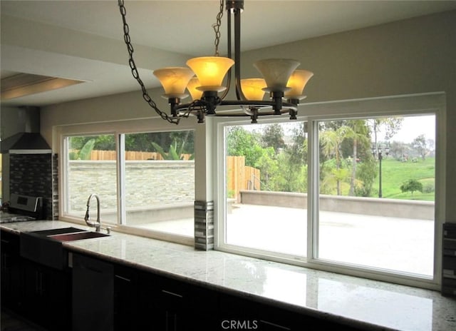 26925 Via Grande, Mission Viejo, CA 92691 - kitchen featuring wall chimney range hood, light stone counters, decorative light fixtures, dark cabinetry, and a sink