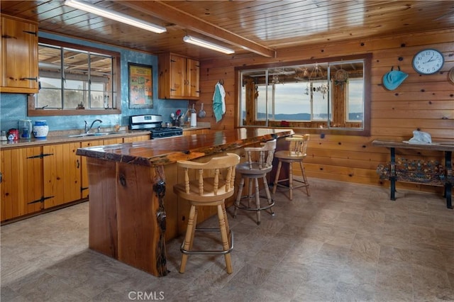 9000 Figueroa Mountain Rd, Los Olivos, CA 93441 - kitchen with gas stove, wooden ceiling, wooden walls, a center island, and a kitchen bar