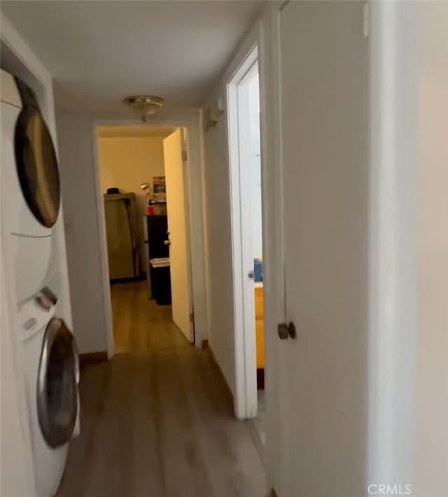 laundry room featuring estacked washer and dryer and light wood finished floors