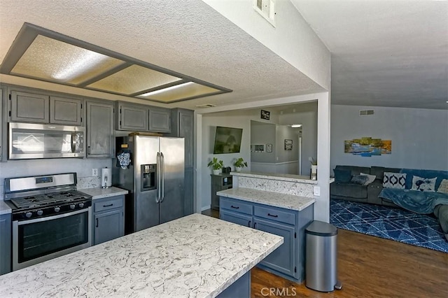 kitchen featuring appliances with stainless steel finishes, dark wood-style flooring, blue cabinets, open floor plan, and light stone countertops