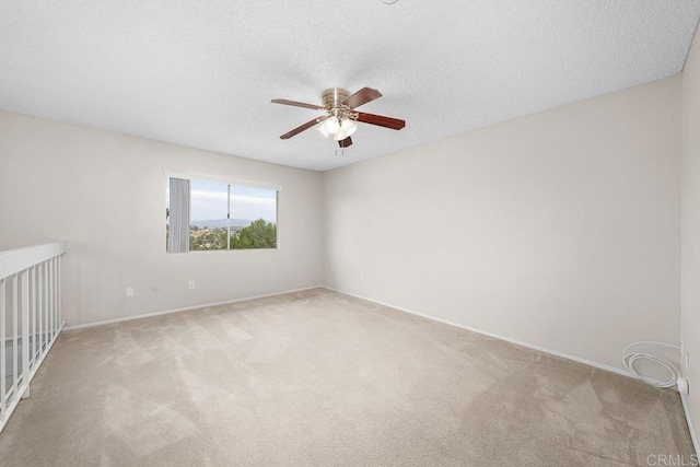 carpeted spare room featuring a ceiling fan, baseboards, and a textured ceiling