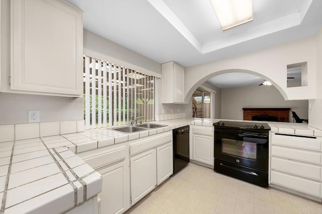 kitchen featuring black appliances, tile countertops, arched walkways, white cabinets, and a sink