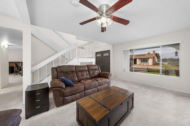 carpeted living room with ceiling fan, stairway, a textured ceiling, and baseboards