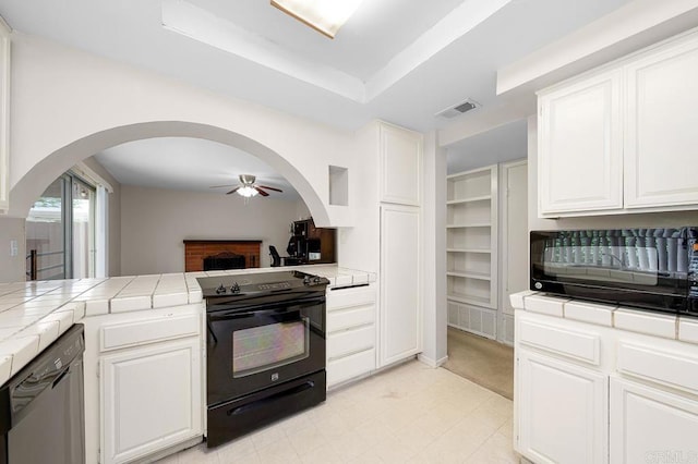 kitchen with tile counters, black appliances, arched walkways, ceiling fan, and white cabinetry