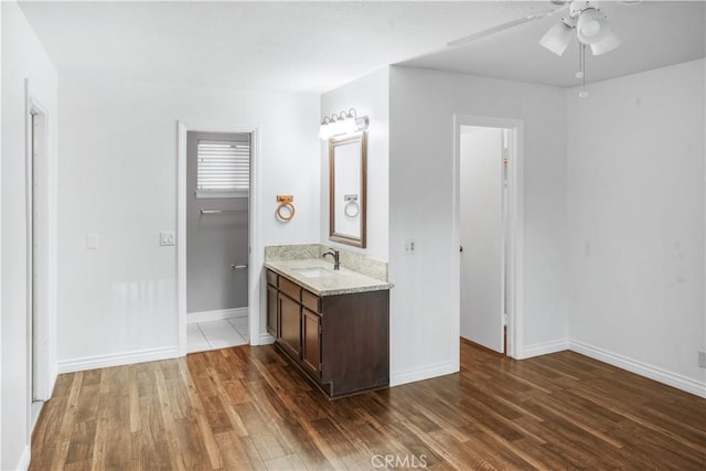 bathroom with wood finished floors, ceiling fan, baseboards, and vanity