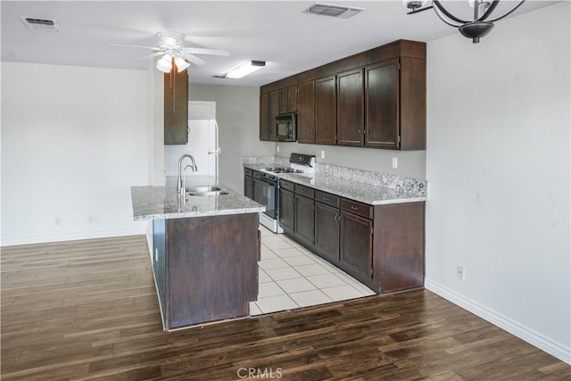 kitchen featuring white appliances, a sink, a ceiling fan, and dark brown cabinetry