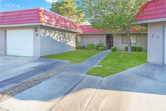 view of front of property with a tiled roof, stucco siding, a front yard, and a garage