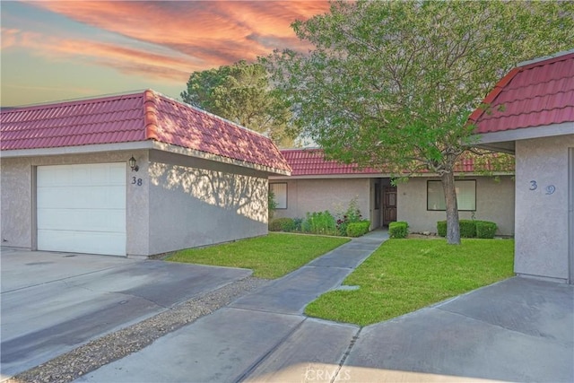 view of front facade featuring a tile roof, stucco siding, and a yard